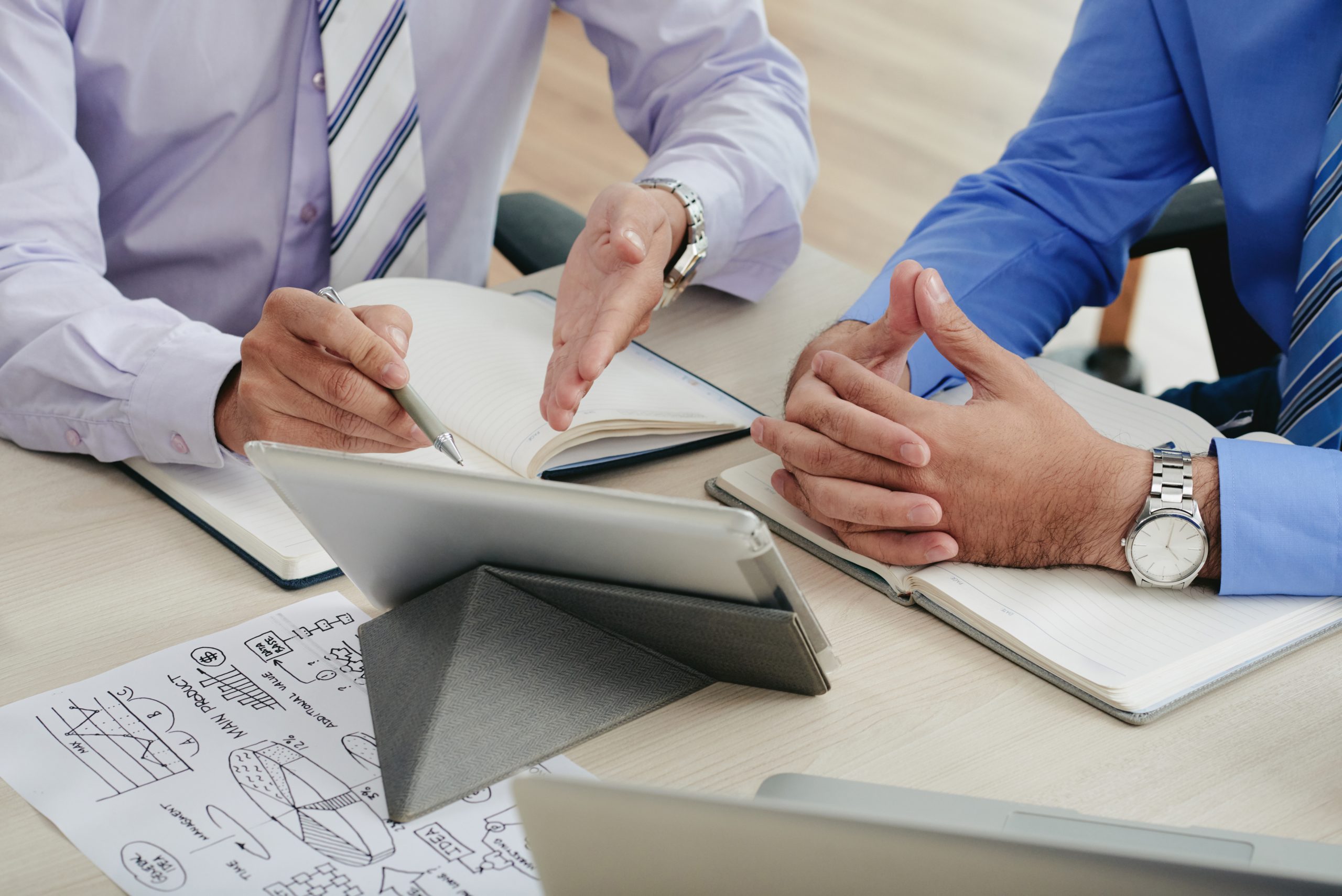 Close-up image of coworkers discussing data on tablet computer screen